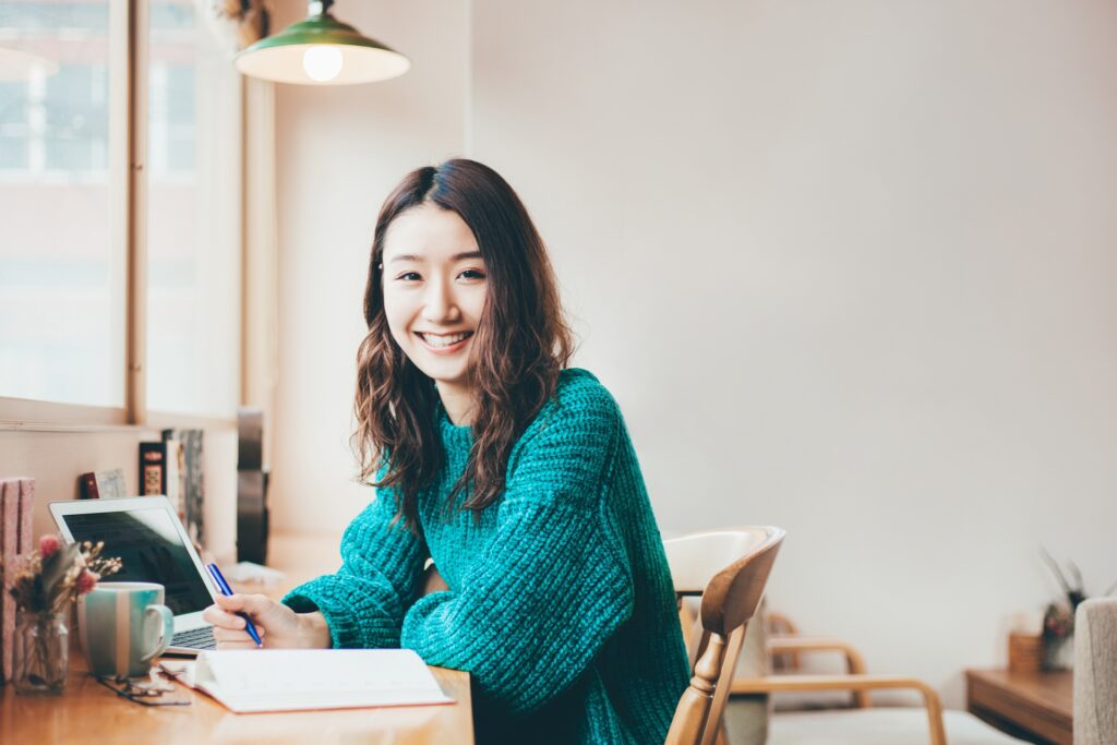 女性が笑顔で机に座っている写真